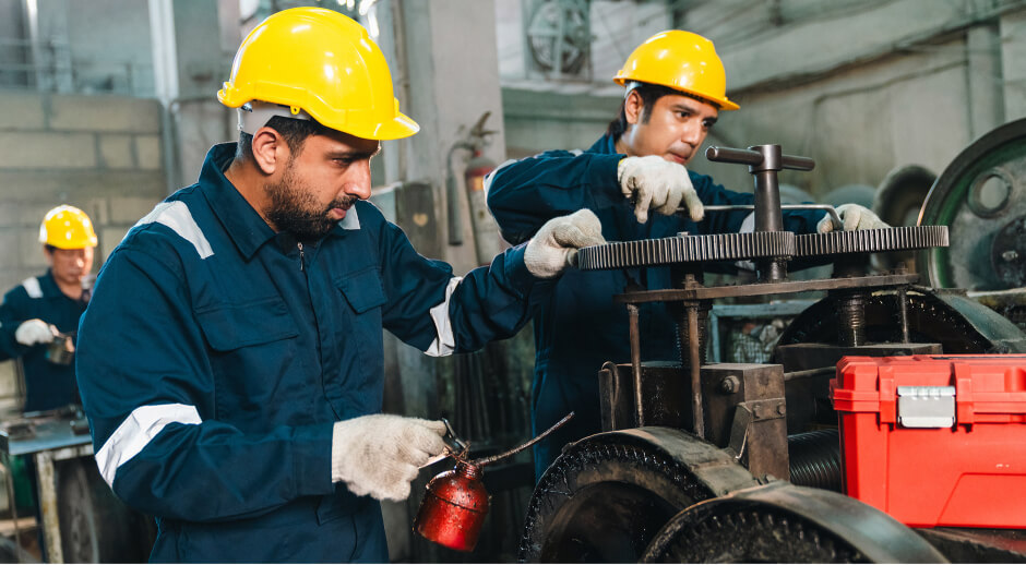 Technicians applying gear oil to industrial machinery